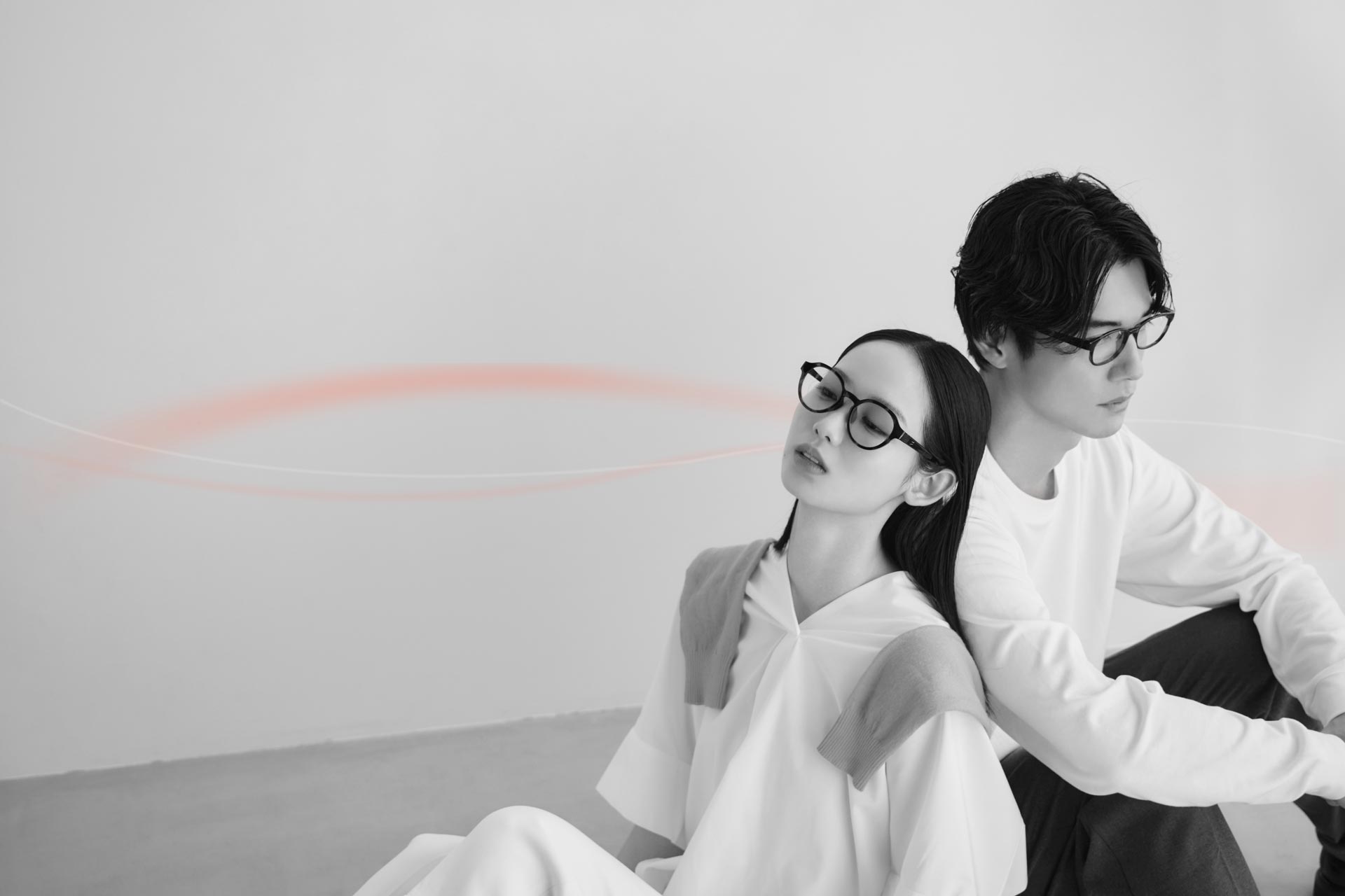 MEGLASSを着用した男女が背中合わせに座り、目もとを休めるような穏やかな表情を見せているライフスタイルイメージ

