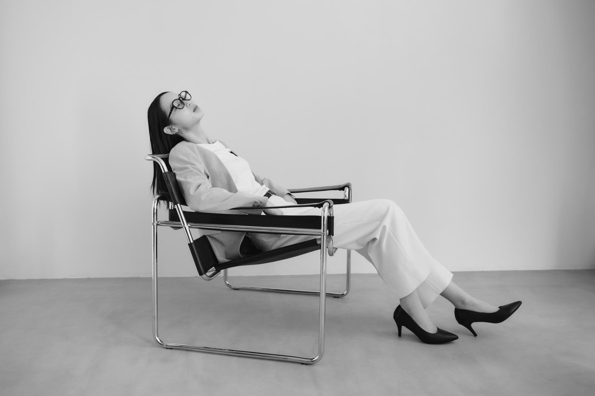 MEGLASSをかけた女性が、目もとを休めるようにリラックスして座っているシーン